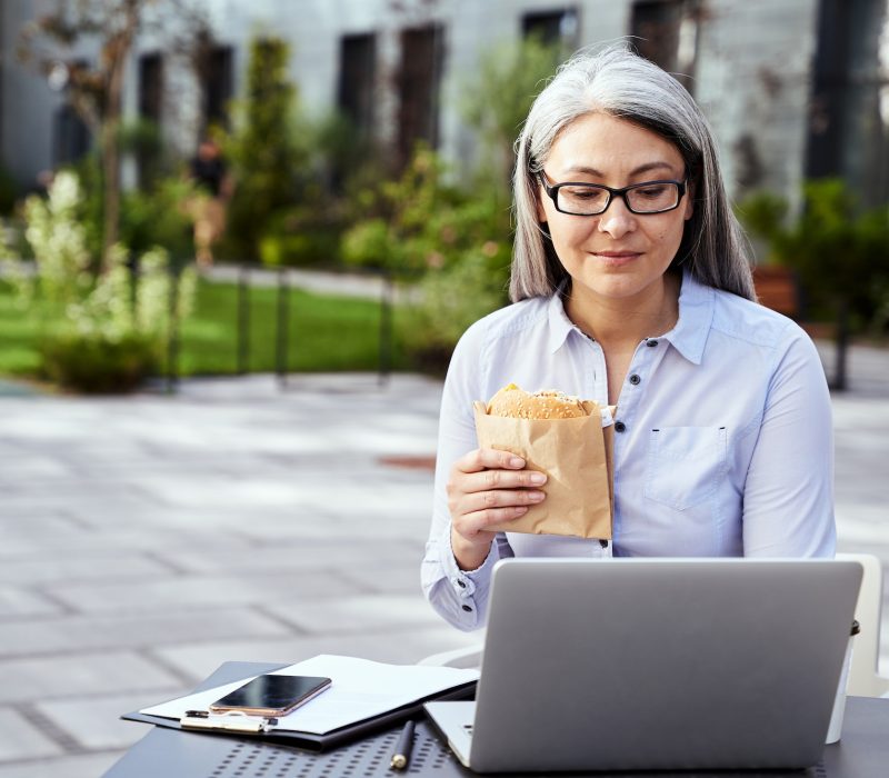 Good-looking business lady working on laptop and having a snack
