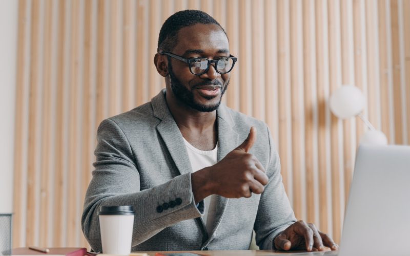 Happy young african american businessman talks online on laptop with client or business partner